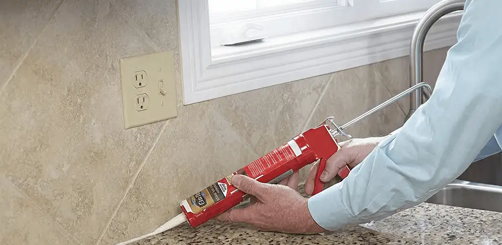 Handyman applying caulk along a kitchen backsplash and countertop seam in Bradenton, FL
