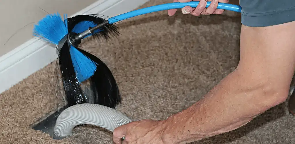 Dryer vent cleaning technician brushing lint from a vent line in Bradenton, FL