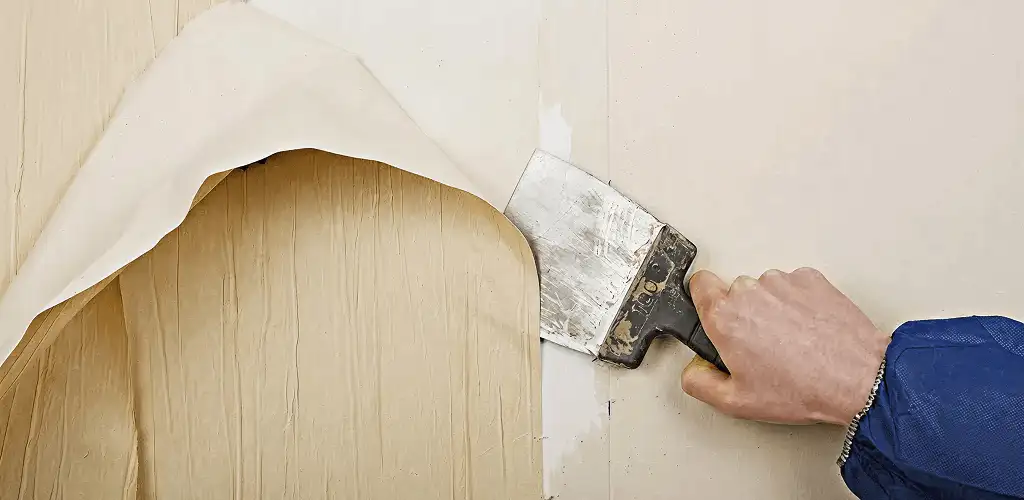 Handyman removing wallpaper with a scraper for wall preparation in Bradenton, FL