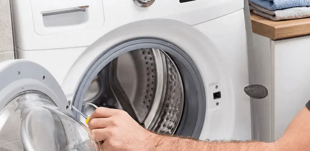 Handyman repairing a front-load washing machine and inspecting the drum in Bradenton, FL