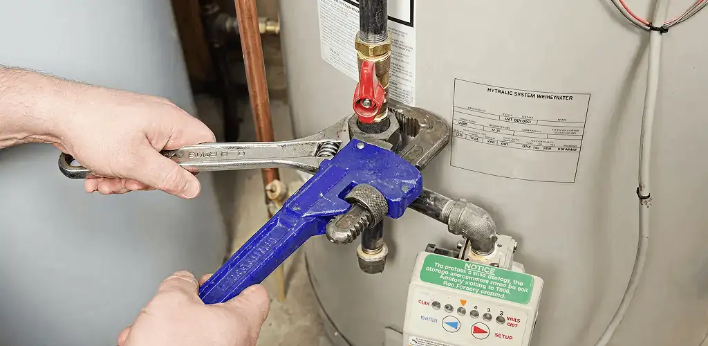 Water heater repair technician tightening the shutoff valve and supply line in Bradenton, FL